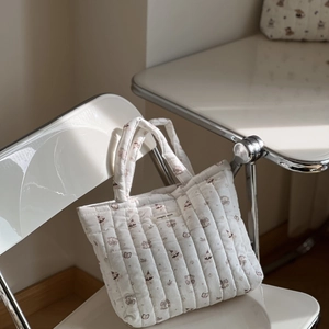 Detailed macro view of white quilted tote bag featuring cute cartoon animal patterns