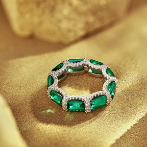Macro shot of silver eternity ring with emerald green gems and micro-pave crystals