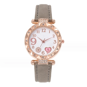 Gros plan d'une montre en quartz or rose avec lunette en strass et bracelet en daim gris