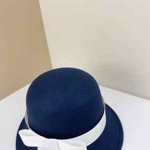 Close-up detail of a navy blue felt school-style bowler hat with white ribbon bow