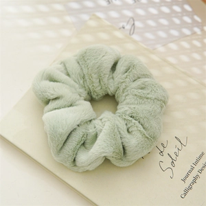 Close-up of soft light green plush scrunchie on an open book under warm natural light