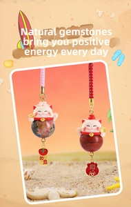 Detail of maneki-neko crystal pendants with agate stones and lucky charms on a beach
