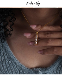 Close-up of a gold necklace featuring three vertical rectangular clear zircon pendants