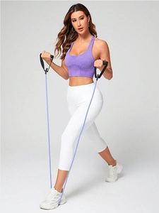 Woman in purple high-impact sports bra and white yoga pants using resistance bands