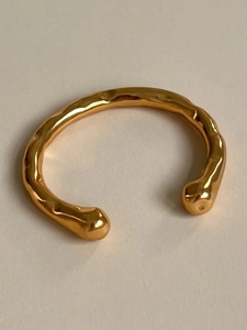 Dettaglio macro del bracciale aperto placcato oro 18K con texture martellata e terminali sferici