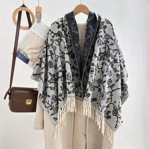 Detailed close-up of a jacquard tassel shawl styled over a coat for autumn warmth