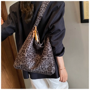 Detail of leopard print suede shoulder bag with colorful beaded charm and soft texture
