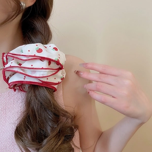 Detail of white floral scrunchie with strawberry print and red ruffle edge on braid