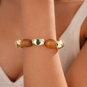 Detail of bohemian acrylic amber beads and gold oval links bracelet on a wrist
