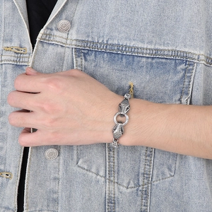 Vue détaillée d'un bracelet tête de serpent argenté style punk porté sur une veste en jean