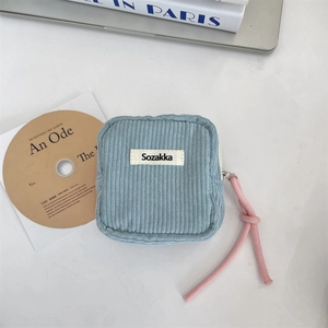 Close-up of blue corduroy cosmetic bag with pink rope zipper and woven logo detail