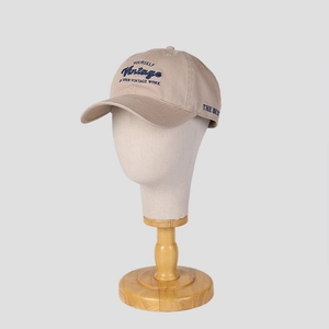 Beige vintage embroidered baseball cap with blue letters on a professional head model