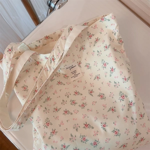 Flat lay of a floral canvas tote bag featuring delicate pink flowers and a woven label
