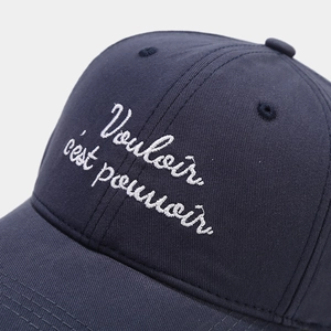 Close-up of cotton baseball cap with white embroidery 'Vouloir c'est pouvoir' detail