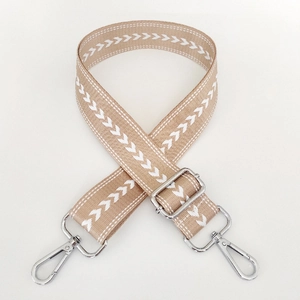 Detail of adjustable nylon shoulder strap with beige arrow pattern and silver metal hooks