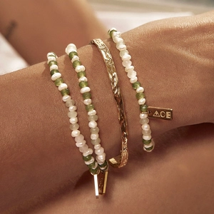 Stackable gold bangle and beaded bracelets with pearls and green stones on model