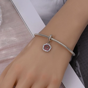 Detail of silver snake chain bracelet featuring a peace pendant with colorful zircons
