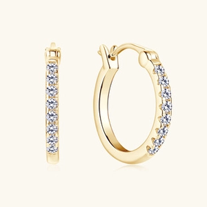 Makroansicht goldener Creolen mit sorgfältiger weißer Zirkon-Pavé-Fassung am Ring