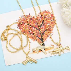 Detailed view of three gold hip hop gun pendants with iced out cubic zirconia stones