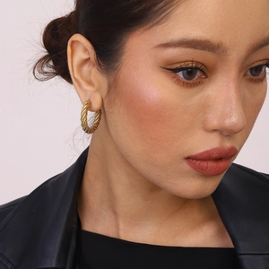 Détail de boucles d'oreilles créoles C torsadées bicolores or et argent sur un modèle
