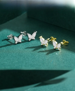 Gros plan de boucles d'oreilles papillon en argent et or avec zircons brillants incrustés