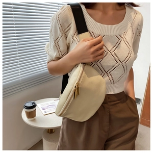 Detail of cream lychee leather waist bag with gold double zippers and wide black strap