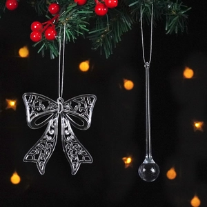 Macro shot of transparent acrylic bow and water drop ornaments on pine branch