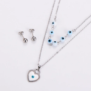 Close-up of heart necklace and blue bead chain with evil eye motif on white background