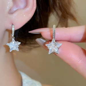 Detailed macro view of silver star earrings with sparkling cubic zirconia on a model
