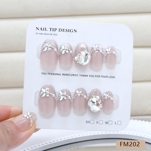 French cat-eye press-on nails with sparkling rhinestones and pearls on display board
