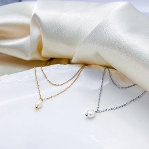 Detail of double-layer pearl necklace in gold and silver finish on white silk