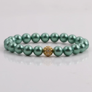 Detail of green pearl bracelet featuring a central golden hollowed-out decorative bead
