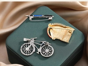 Detail view of the secure safety pin clasps on vintage bicycle and pen brooches