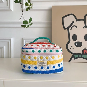 Détail de la trousse de maquillage matelassée avec pois colorés, rayures et poignée verte