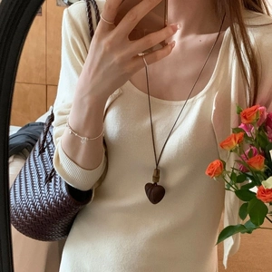 Retro wooden heart pendant necklace with dark cord on a model wearing an autumn cardigan