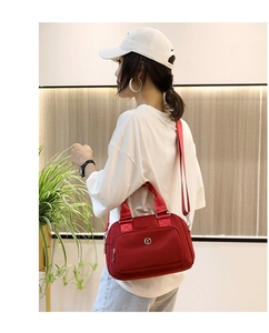 Detailed view of a red nylon crossbody bag with circular metal logo on a female model