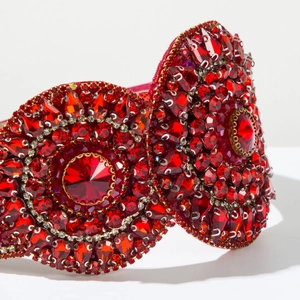 Close-up of luxury wide headband with deep red crystals and intricate rhinestone patterns