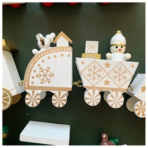 Close-up of white wooden Christmas train with gold snowflake details on green background