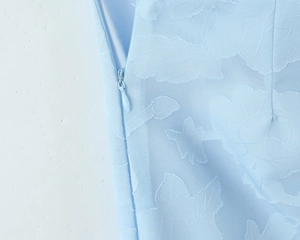 Détail du tissu jacquard floral bleu clair avec une fermeture éclair latérale invisible