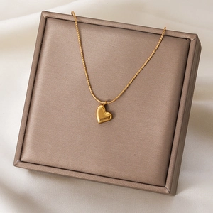 Collier avec pendentif cœur doré élégamment disposé sur un coffret sur fond de soie blanche