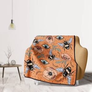 Detail of orange flannel throw blanket with retro bee and floral patterns on sofa