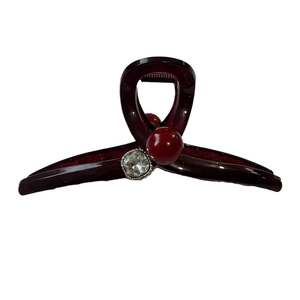 Grande pince à cheveux en acrylique bordeaux avec perle et strass sur fond blanc