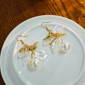 Detail of French vintage earrings with white petals and pearls on a ceramic dish