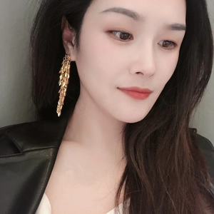 Exaggerated gold leaf tassel long earrings shown on model for a trendy fashion look