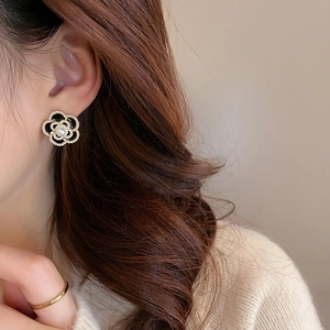 Close-up of model wearing a vintage camellia pearl earring with gold trim and enamel