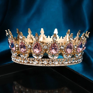 Detailed close-up of luxurious gold crown with pink teardrop gems and sparkling rhinestones