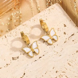 Elegant gold butterfly earrings with shell inlay on minimalist textured stone display