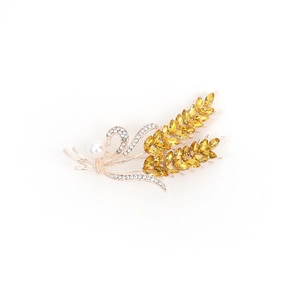 Golden wheat stalk brooch with yellow crystals and white pearl on white background
