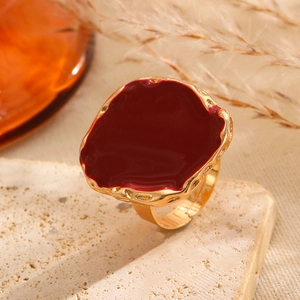 Close-up of a vintage irregular red enamel ring on a beige stone with dried flowers