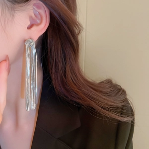 Macro shot of silver knot tassel earrings with long metallic chains on female model
